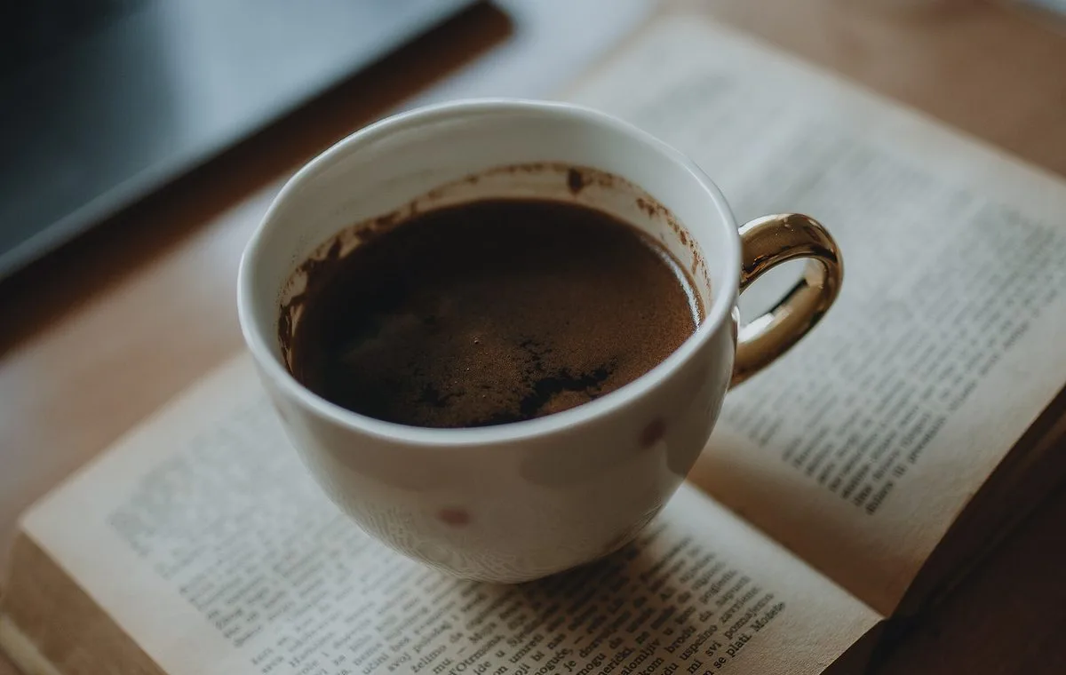 Cup of coffee resting on an open book